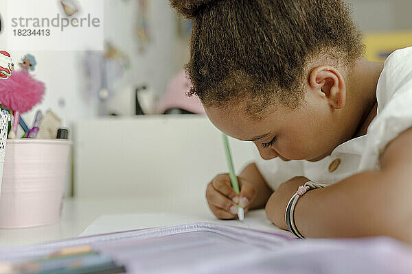 Mädchen zeichnet am Schreibtisch auf Papier