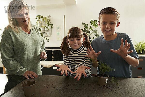 Lächelndes Mädchen und Junge zeigen schmutzige Hände und stehen der Mutter zu Hause zur Seite