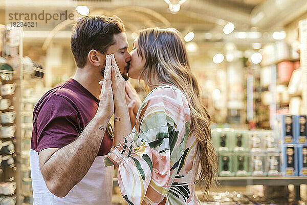 Zärtlicher Mann und Frau küssen sich im Laden