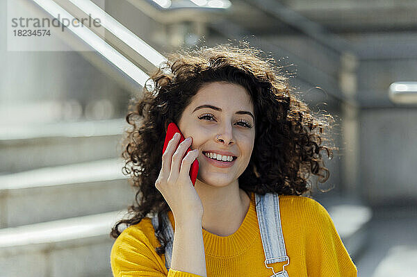 Schöne Frau mit lockigem Haar  die mit dem Handy spricht