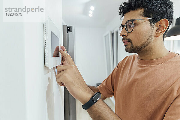 Mann benutzt Smart-Home-Gerät an der Wand