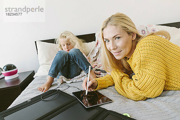 Mutter hält digitalisierten Stift mit Tablet-PC von Tochter auf dem Bett