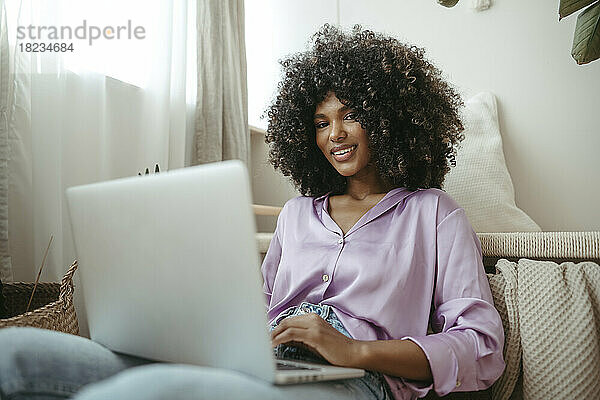 Lächelnde Afro-Frau mit Laptop zu Hause