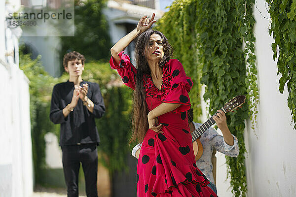 Flamenco-Tänzerin tritt mit Gitarrist in der Nähe der Wand auf