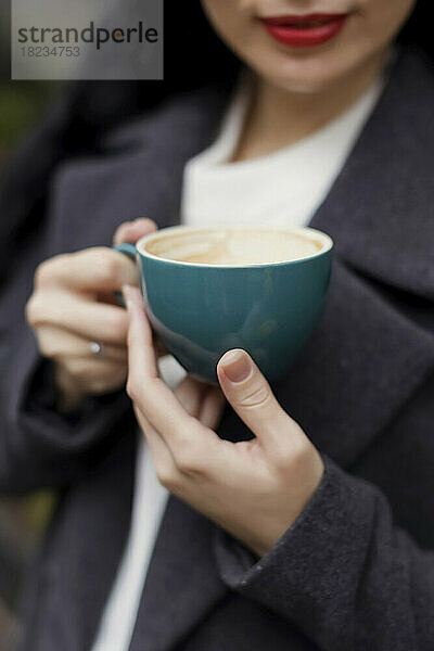 Hände einer Frau  die eine Kaffeetasse hält