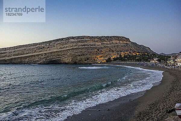 Griechenland  Kreta  Matala  Strand von Matala und Höhlen an den Klippen in der Abenddämmerung