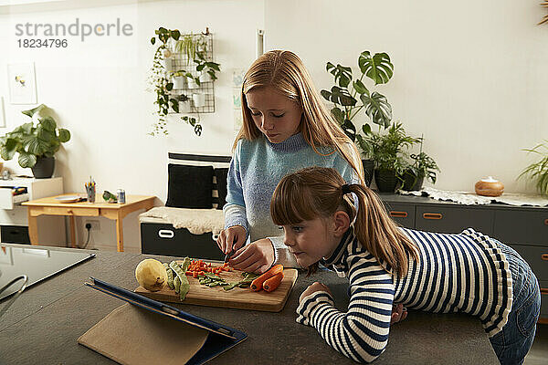 Mädchen bereitet Essen mit Schwester zu Hause per Tablet-PC zu