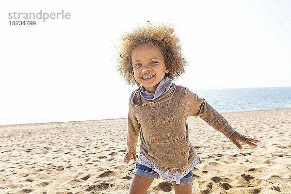Glückliches süßes Mädchen mit Afro-Frisur  das am Strand genießt