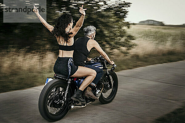 Frau genießt es  mit Mann Motorrad auf der Straße zu fahren