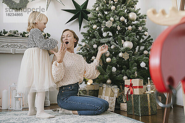 Tochter und Mutter schmücken zu Hause den Weihnachtsbaum