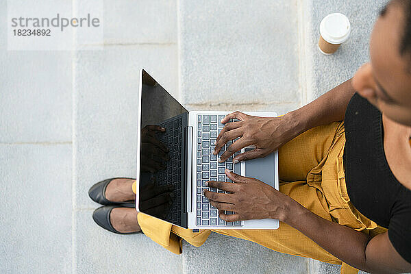 Freelancer working on laptop sitting at staircase