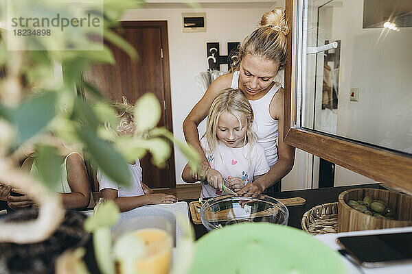 Mutter und Tochter bereiten gemeinsam in der Küche einen Salat zu