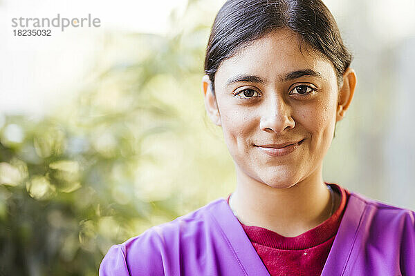 Lächelnde junge Pflegekraft in lila Uniform