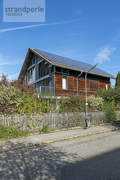 Deutschland  Bayern  München  Elektroroller links vor einem modernen Passivhaus mit Sonnenkollektoren