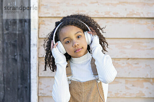 Mädchen hört Musik über Kopfhörer vor der Wand