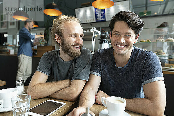 Lächelnder Mann mit Freund  der im Café sitzt
