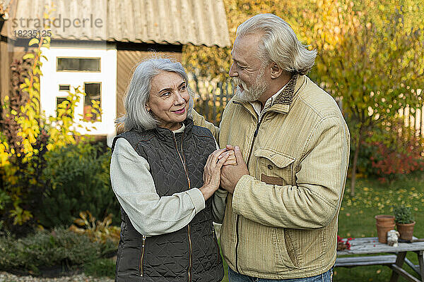 Liebevolles Seniorenpaar hält Händchen im Garten