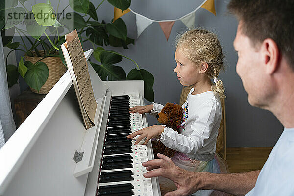 Mädchen liest Noten und spielt zu Hause Klavier