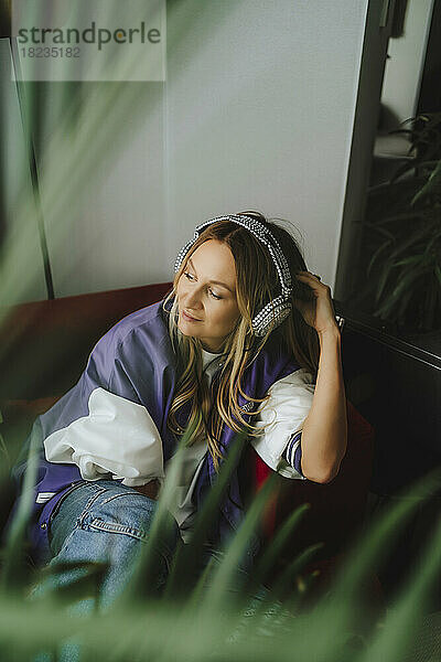 Lächelnde Frau mit Kopfhörern auf dem Sofa im Aufnahmestudio