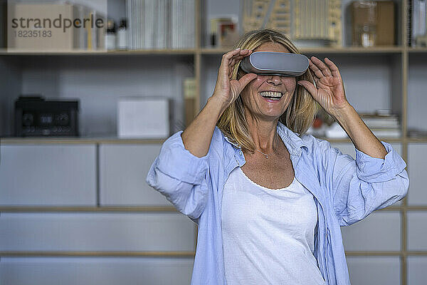 Glückliche reife Frau  die zu Hause eine Virtual-Reality-Brille trägt