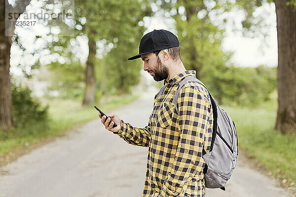 Mann mit Mütze und Smartphone unterwegs