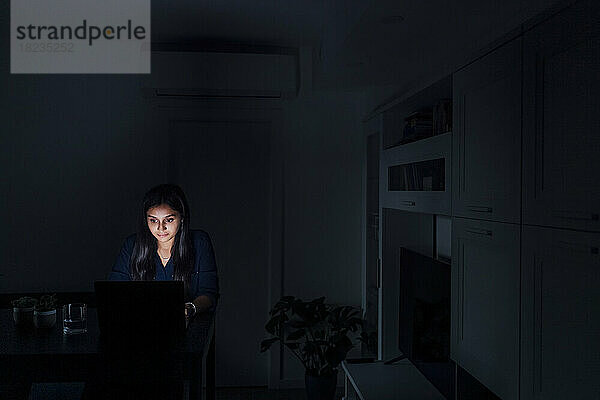 Junge Frau benutzt Laptop im Wohnzimmer zu Hause
