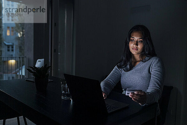 Frau mit Kreditkarte beim Online-Einkauf per Laptop zu Hause
