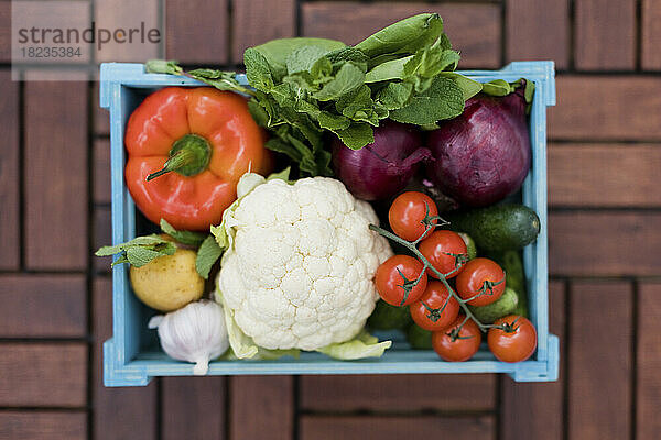 Organic fresh vegetables in blue crate on table