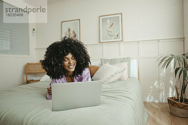 Afro-Frau benutzt Laptop zu Hause im Bett