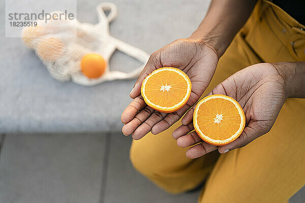 Frau hält Orangenscheiben in der Hand