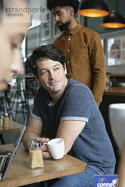 Nachdenklicher Mann mit Kaffeetasse sitzt im Café
