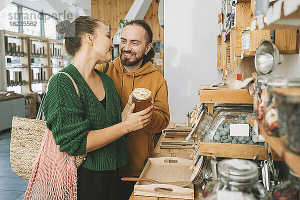 Lächelndes Paar mit Honigglas im Supermarkt