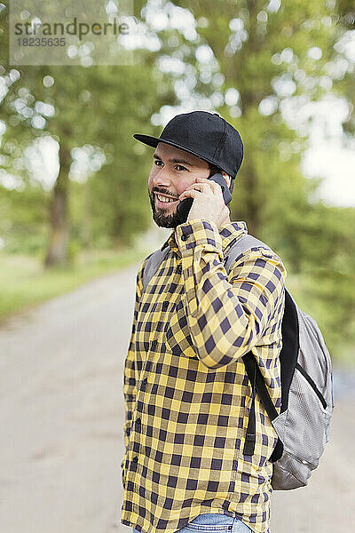 Lächelnder Mann  der unterwegs mit dem Mobiltelefon spricht