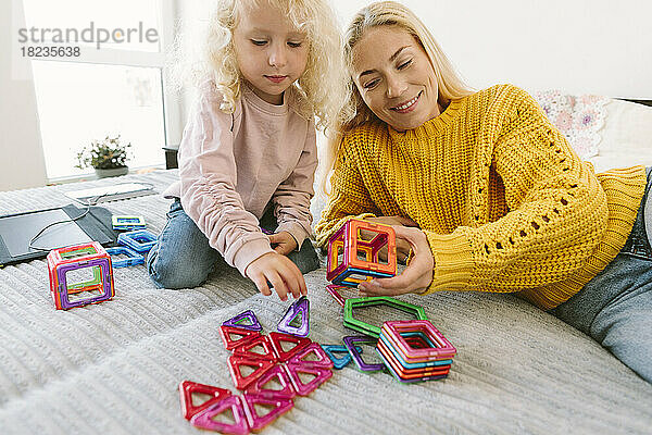 Glückliche Mutter und Tochter spielen zu Hause im Bett