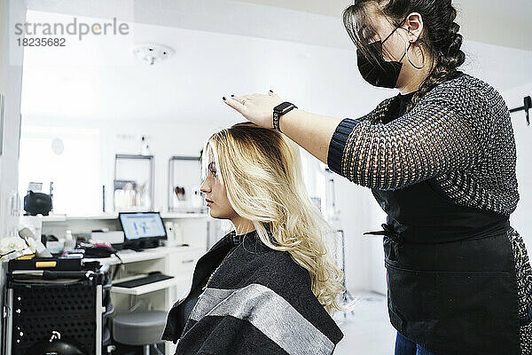 Friseur frisiert die Haare des Kunden im Salon