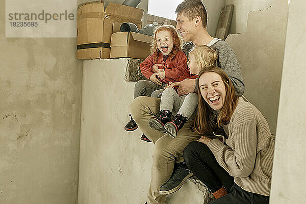 Glückliche Familie sitzt auf der Treppe und genießt das unvollständige Zuhause