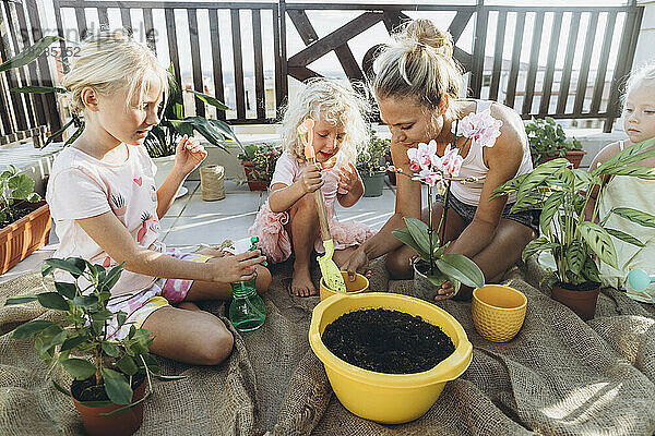 Mutter und Töchter pflanzen gemeinsam Blumen auf der Dachterrasse