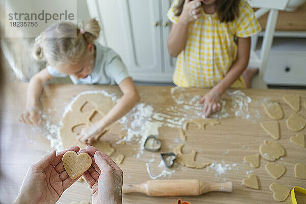Hände einer Frau  die zu Hause mit Mädchen Kekse zubereitet