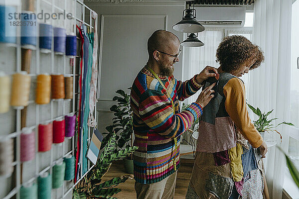Modedesignerin probiert Patchwork-Kleid an Kollegin in Werkstatt an