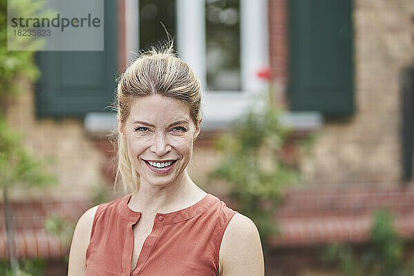 Lächelnde Frau vor dem Haus