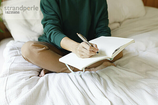 Frau schreibt Notizen in Tagebuch