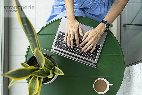 Hände einer Geschäftsfrau  die am Tisch einen Laptop benutzt