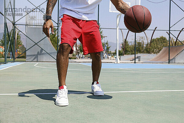 Mann übt an einem sonnigen Tag Basketball auf dem Sportplatz