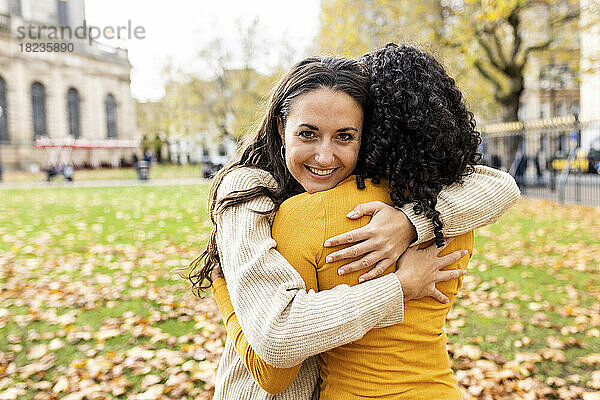 Lächelnde Frau umarmt Freundin im Herbstpark