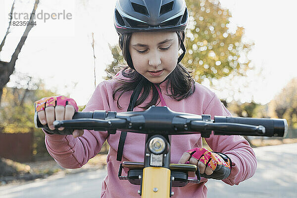 Mädchen mit Helm benutzt Smartphone auf Elektroroller