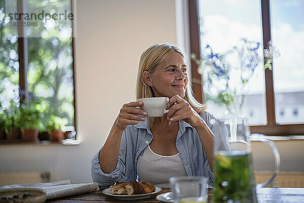 Reife Frau hält zu Hause eine Tasse Kaffee