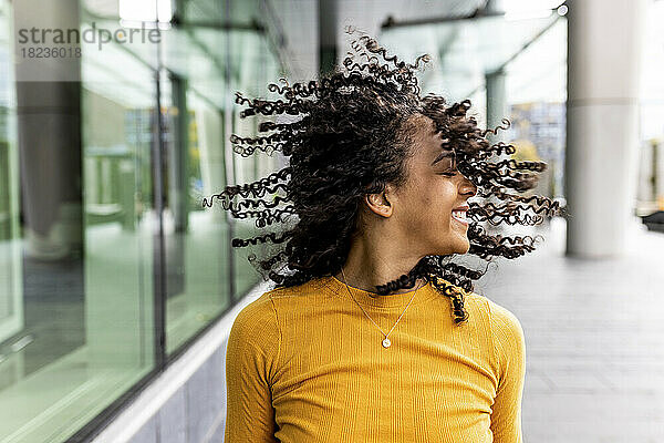 Carefree woman tossing hair on footpath