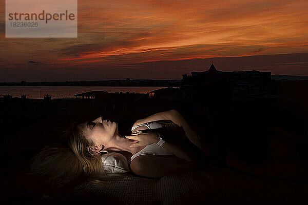 Frau mit geschlossenen Augen entspannt sich bei Sonnenuntergang