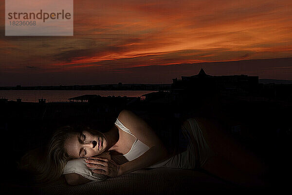 Woman with eyes closed sleeping at sunset