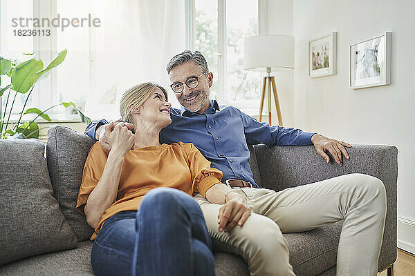 Lächelndes Paar hält sich zu Hause auf dem Sofa an den Händen